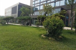 A modern building with a grassy area and trees in front. - Qingcheng Hotel (Qinghe)