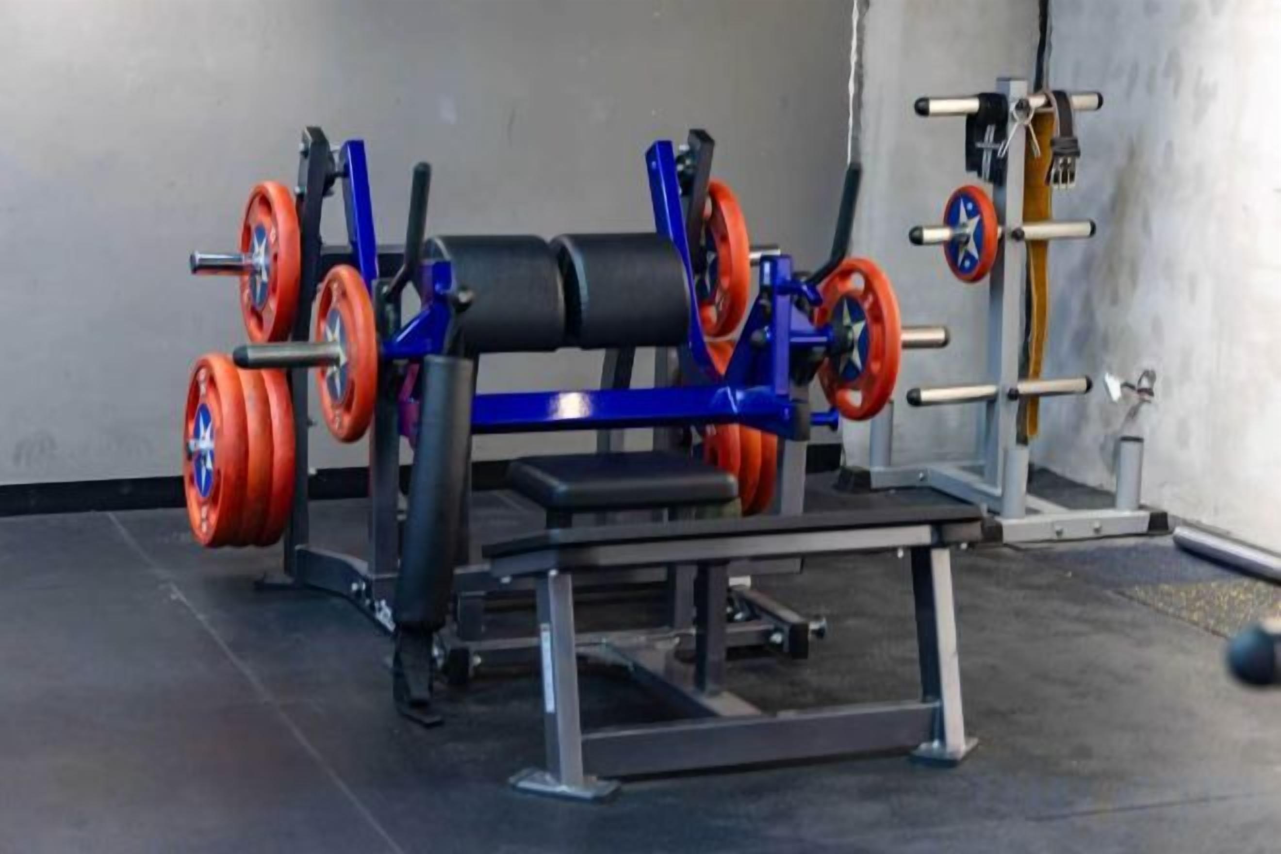 A gym with weightlifting equipment including a bench press and barbells.