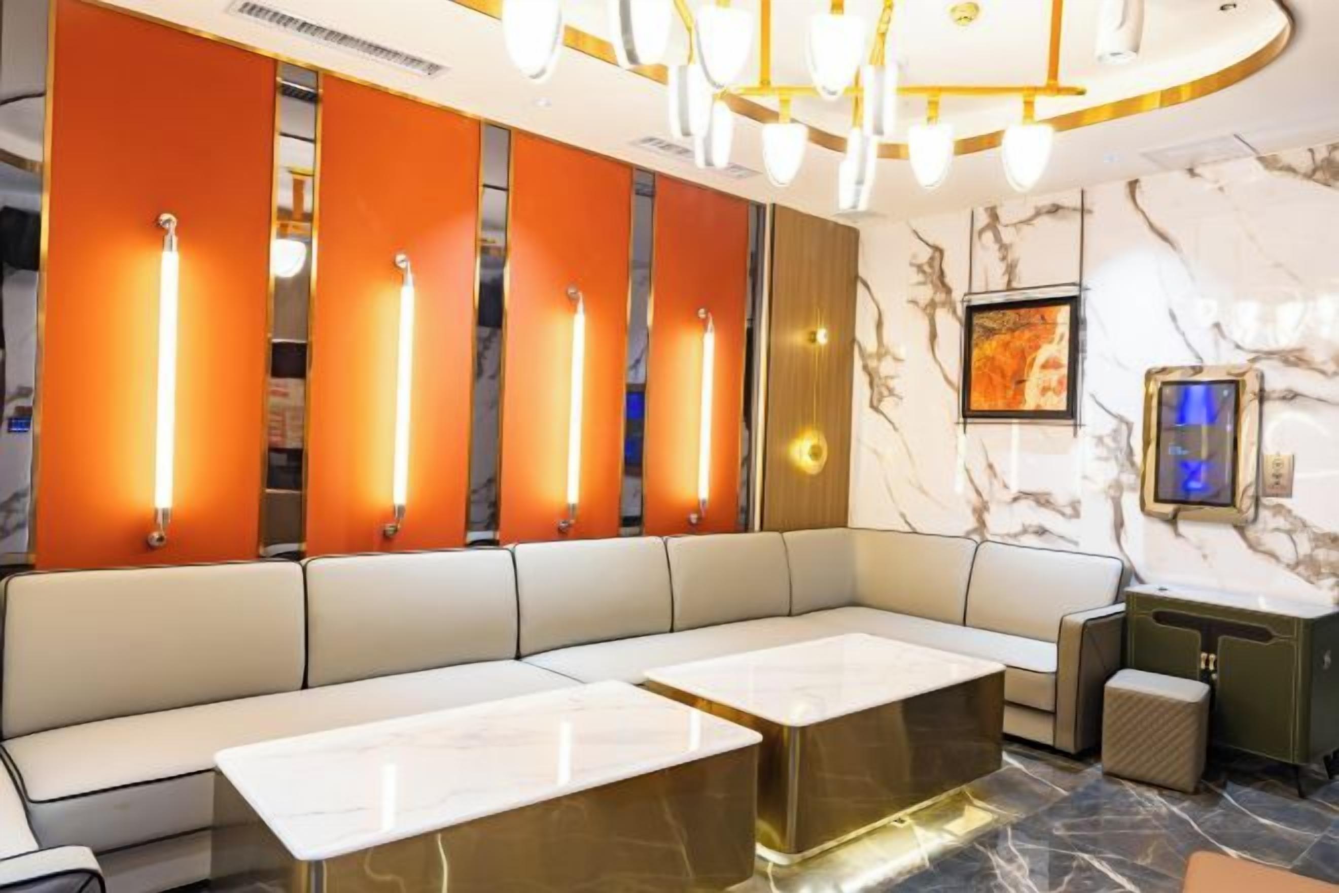 A modern hotel lobby with seating areas, a marble wall, and a framed artwork.