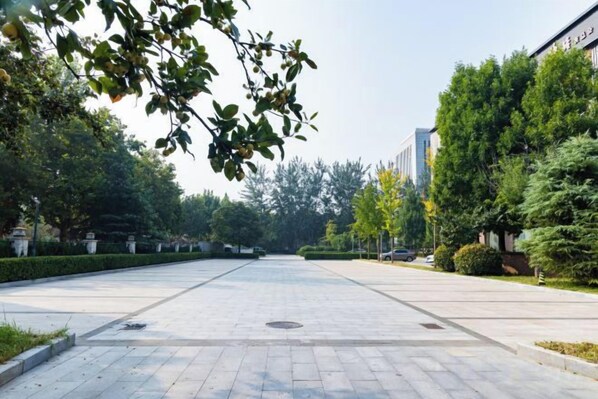 A paved pathway with trees and a building on the right. - Qingcheng Hotel (Qinghe)