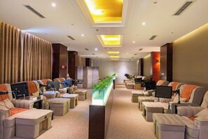 A hotel room with a long, narrow layout featuring a central walkway, multiple seating areas with chairs and tables, and a television screen on each side. - Qingcheng Hotel (Qinghe)