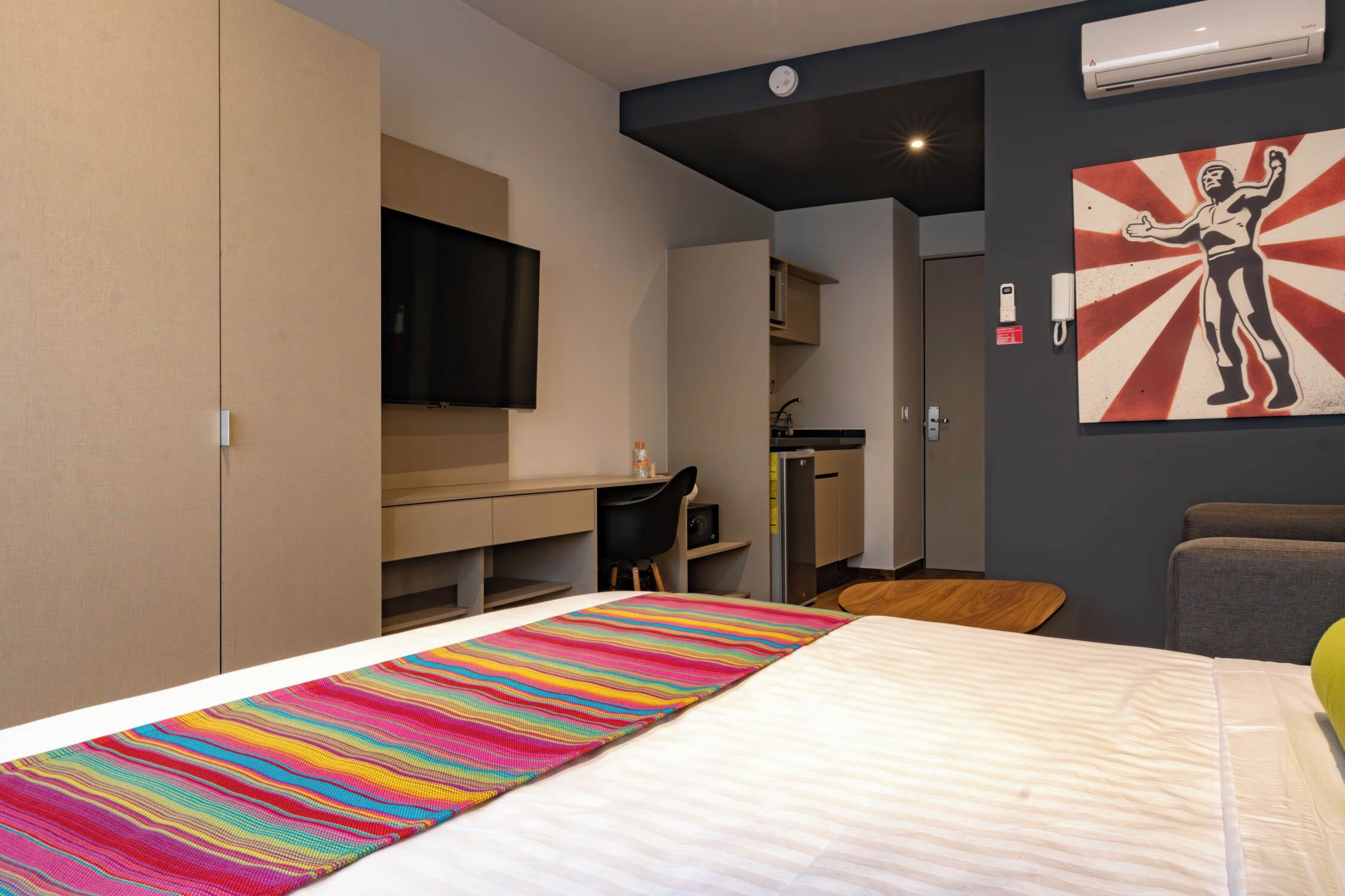 Een hotelkamer met een bed, een bureau, een stoel, een televisie en een schilderij aan de muur.