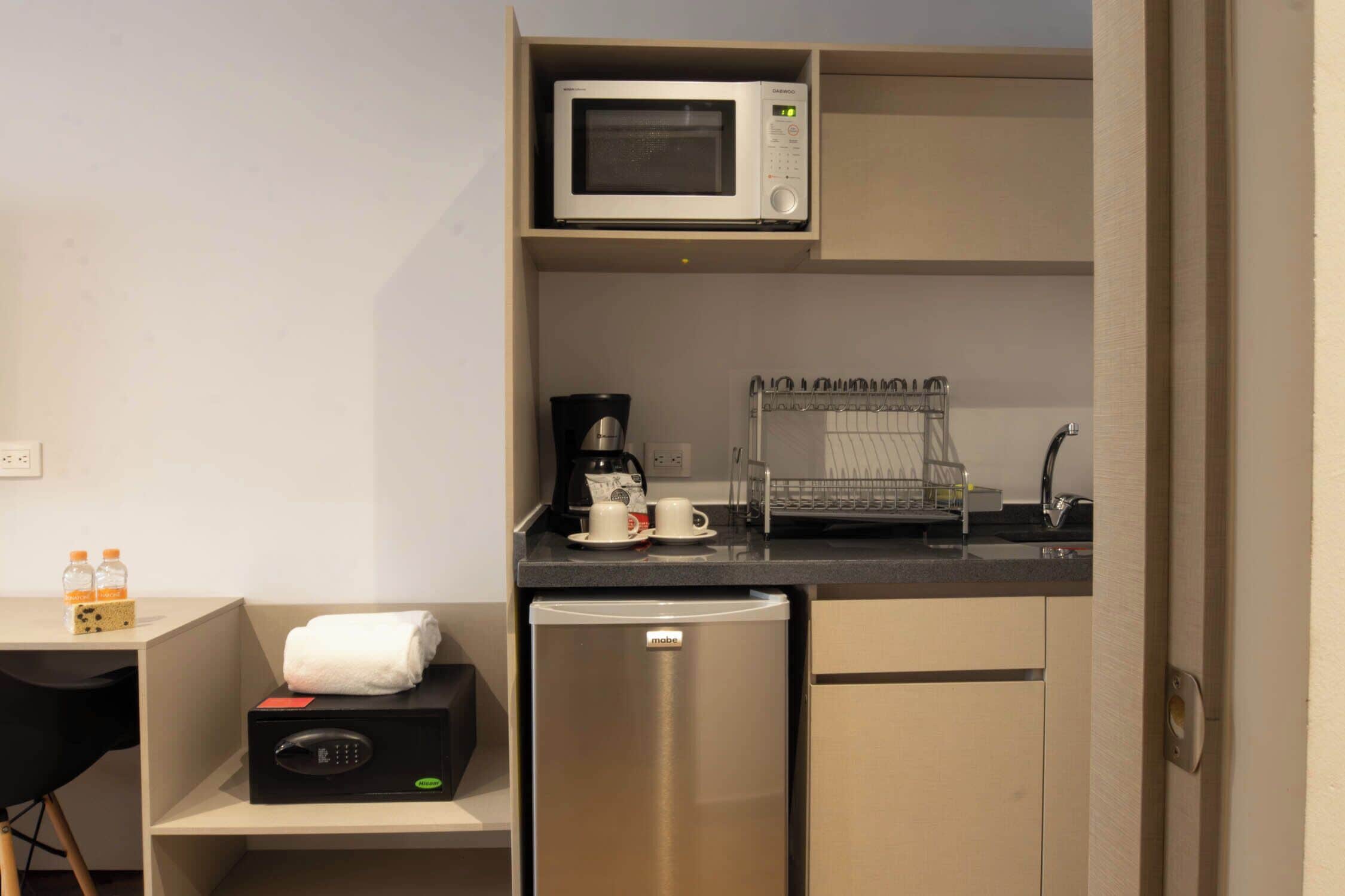 A compact kitchenette with a microwave, coffee maker, and a mini-fridge.