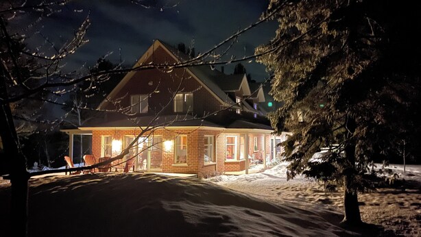 A snow-covered landscape with a house illuminated by warm lights.
