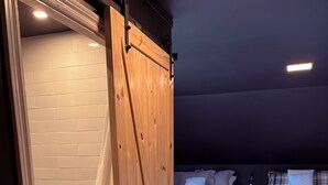 A room with two beds, a sliding door, and a tiled shower area.