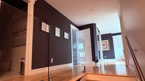 A modern interior with a wooden staircase, dark walls, and a glass door leading to another room.