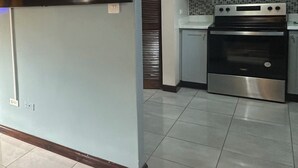 Una cucina moderna con forno integrato e microonde, uno schienale piastrellato e un lampadario a soffitto.
