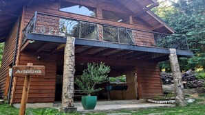 A wooden cabin with a balcony, a sign reading "Araucaria," and a large green planter in front. - cabañasmapulauquen (Villarrica)