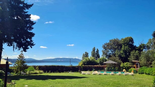 A grassy outdoor area with a pool, lounge chairs, and a gazebo. - cabañasmapulauquen (Villarrica)