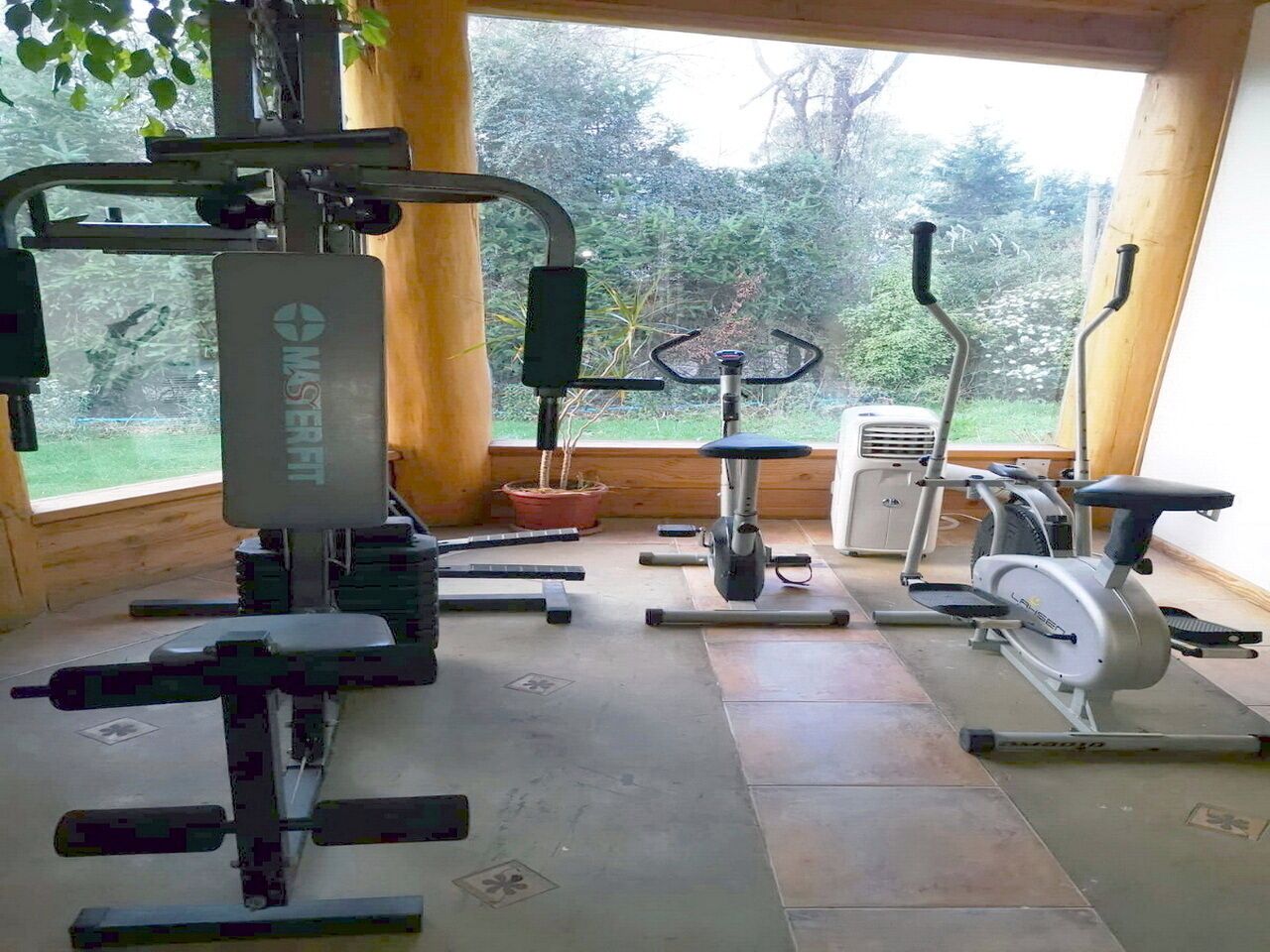 A gym with various exercise equipment including a multi-gym, a stationary bike, and a bench press.