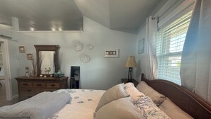 A bedroom with a bed, a dresser, a mirror, and a window with blinds.