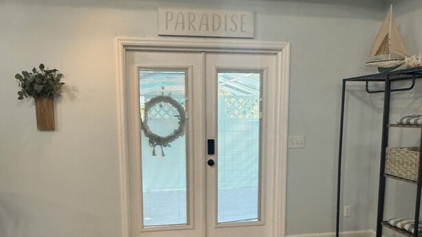 A double door with frosted glass panels, a small wreath, and a sign above reading "PARADISE".