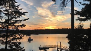 En stilla sjö vid solnedgången, med en brygga och en båt.