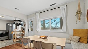 A modern kitchen with a wooden dining table, chairs, and a built-in oven.
