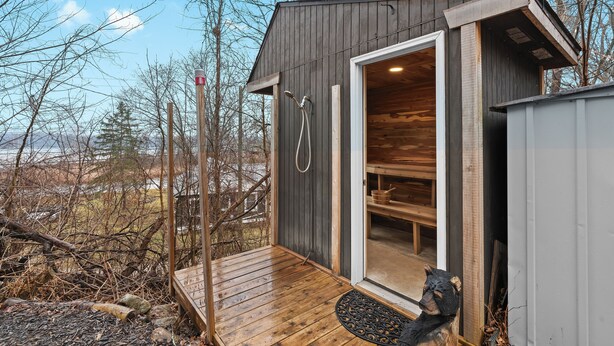 A wooden cabin with a wooden deck, a door leading inside, and a view of the surrounding landscape.