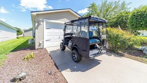 Een zwarte golfkar geparkeerd voor een garage.