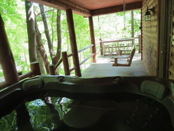 A hot tub on a wooden deck with a view of a forested area. - Southern Comfort Cabin (Rockbridge)