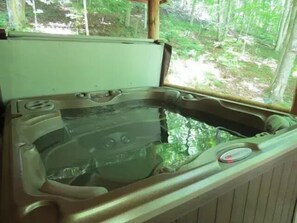 Un jacuzzi con vistas a una zona boscosa a través de una ventana.