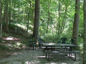 A picnic table with chairs in a forested area.