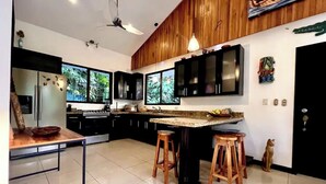 Une cuisine moderne dotée d’un îlot central, de meubles de rangement noirs et d’une grande fenêtre.