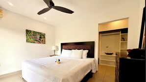Une chambre d’hôtel équipée d’un lit, d’un ventilateur de plafond, d’œuvres d’art et d’une armoire.