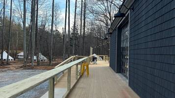 A wooden deck with a railing, leading to a building with large windows.