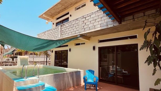 A pool with steps leading into it, a blue chair, and a covered patio area. - CASA MARIA'S PUERTO ESCONDIDO OAXACA MEXICO. (Puerto Escondido)
