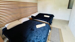 A room with two beds, a wooden slatted headboard, a small bedside table, and a wall-mounted air conditioner. - CASA MARIA'S PUERTO ESCONDIDO OAXACA MEXICO. (Puerto Escondido)