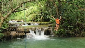 A person swinging on a rope over a waterfall in a forested area. - CASA MARIA'S PUERTO ESCONDIDO OAXACA MEXICO. (Puerto Escondido)
