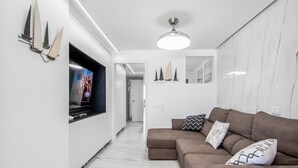 A modern living room with a large flat-screen TV, a brown sectional sofa, and a marble floor. - Endless Seaview Patalavaca (Patalavaca)