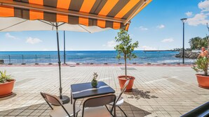 A seaside patio with a striped awning, a table with chairs, and a view of the ocean. - Endless Seaview Patalavaca (Patalavaca)