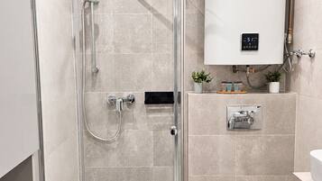 Ein modernes Badezimmer mit einer glasumrandeten Dusche, Toilette und einem eingebauten Warmwasserbereiter.