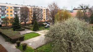 A multi-story residential building with balconies, a parking area, and a small garden.