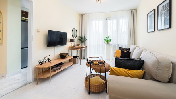 A modern living room with a sofa, television, and a dining area.