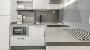 A modern kitchen with white cabinetry, a built-in oven, a coffee maker, and a stainless steel range hood.