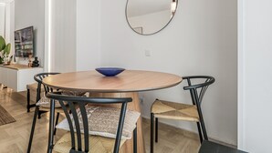 A modern dining area with a round wooden table, black chairs, a blue bowl, and pendant lighting.