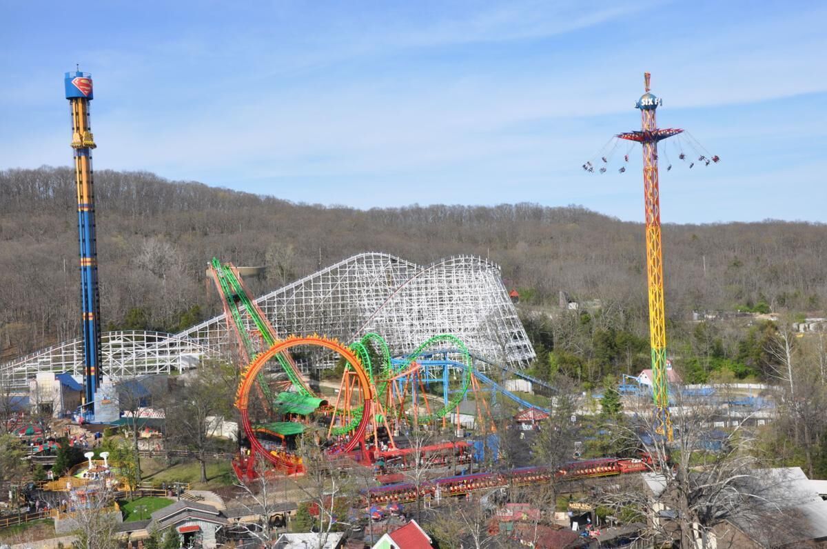 A theme park with various rides and structures, including a tall tower and a roller coaster.