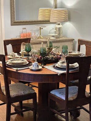 A dining table set with plates, glasses, and a vase.