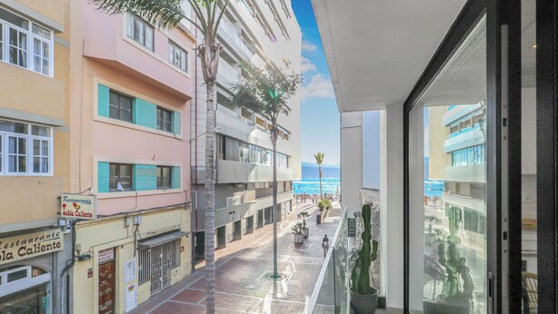A balcony with a view of the beach and a building with a restaurant sign.