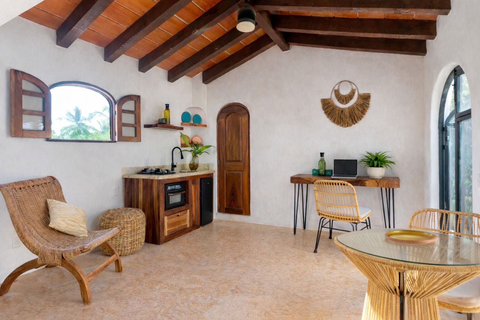 Una cocina acogedora con armarios de madera, un comedor con sillas de mimbre y un ventanal grande.
