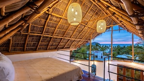 A room with a bed, a balcony, and a view of palm trees and a sunset. - Amari Boutique Hotel Sayulita (Sayulita)