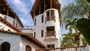 A white building with a thatched roof, a pool, and tropical plants. - Amari Boutique Hotel Sayulita (Sayulita)
