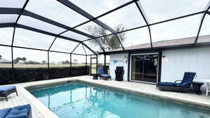 Une piscine couverte avec des chaises longues et un barbecue.