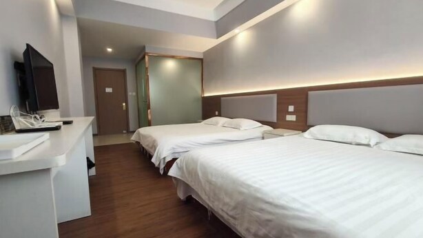 A hotel room with two beds, a desk, a television, and a door leading to another room. - Shijiazhuang Yiguang Hotel (Shijiazhuang)