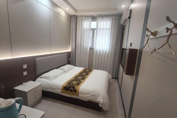 A modern hotel room with a bed, bedside table, and a window with curtains.