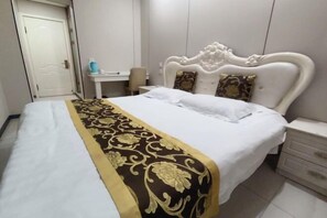 A hotel room with a large bed, a bedside table, a desk, and a chair. - Shijiazhuang Yiguang Hotel (Shijiazhuang)