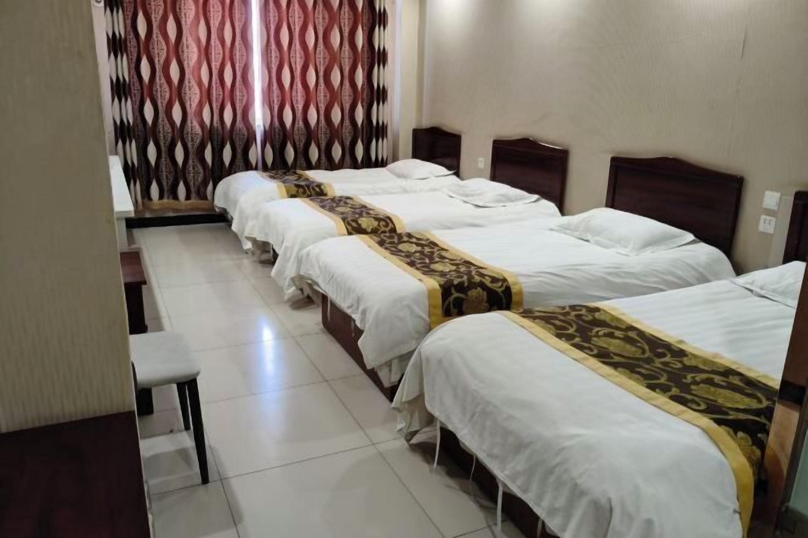 Habitación de hotel con tres camas individuales, un escritorio pequeño y una silla.