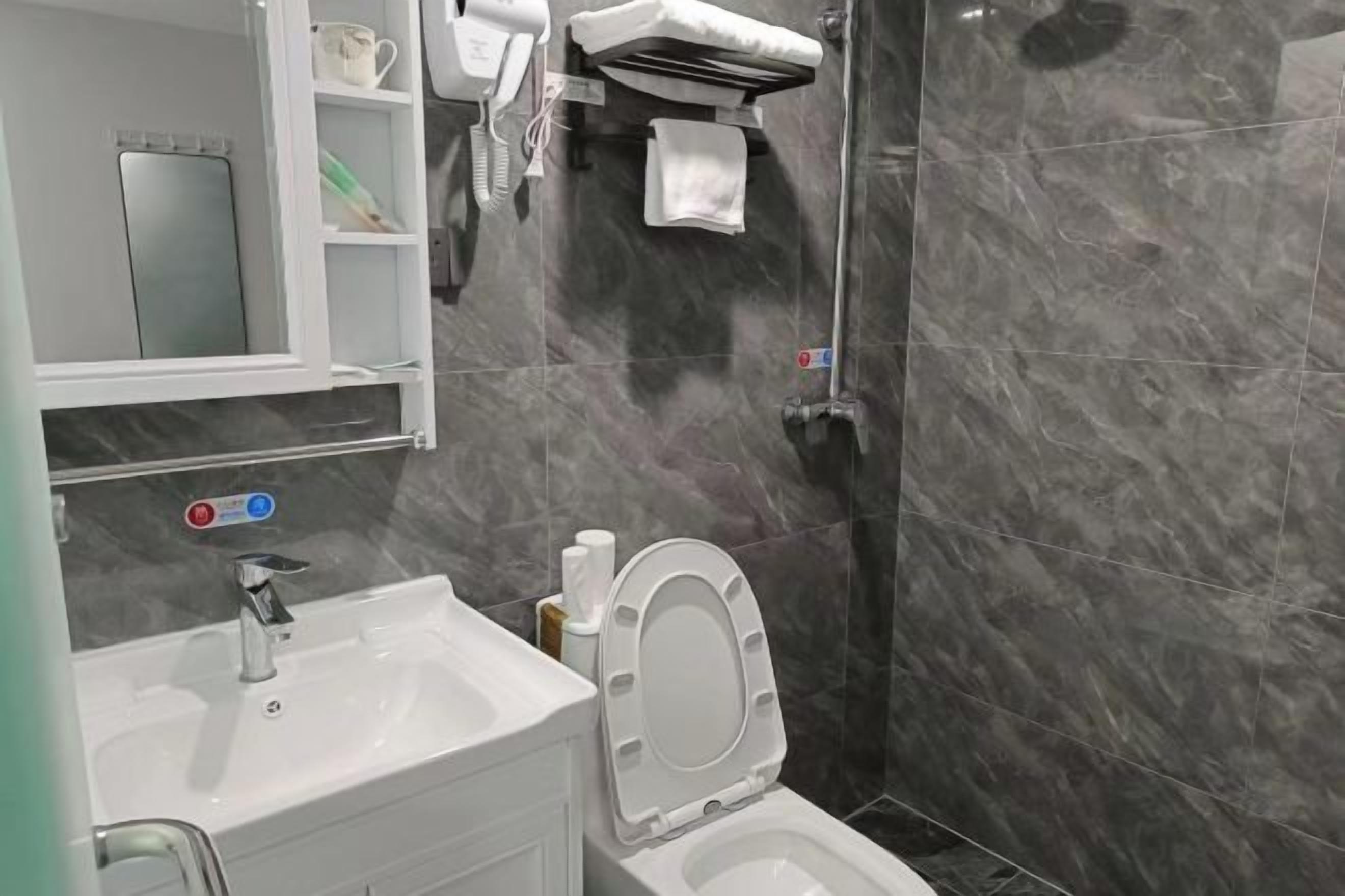 A bathroom with a white sink, a mirror, a towel rack, and a toilet.