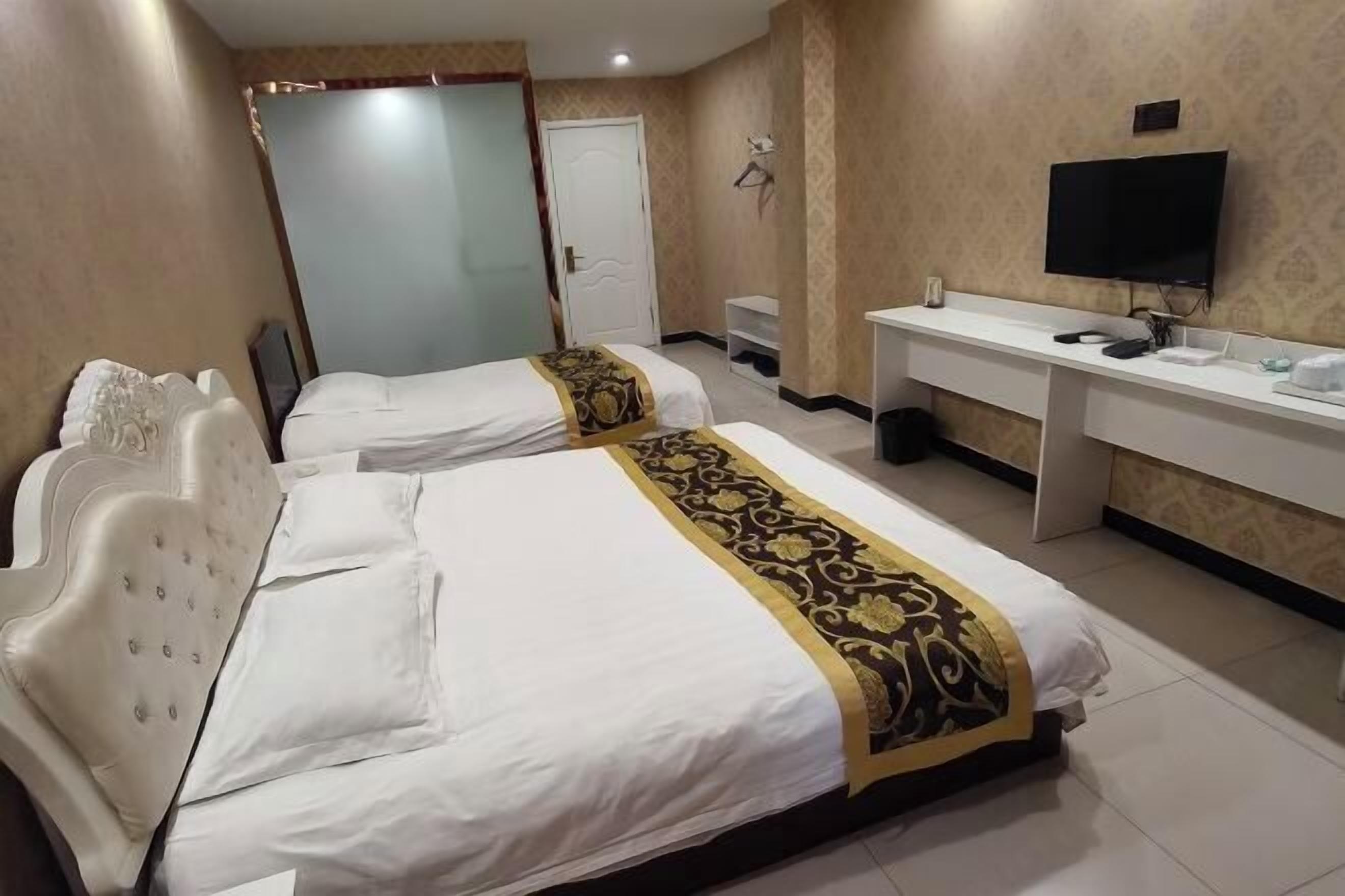 A hotel room with two beds, a desk, a television, and a wardrobe.