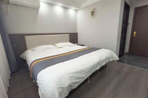 A hotel room with a bed, a nightstand, a wall-mounted light, and a door. - Shijiazhuang Yiguang Hotel (Shijiazhuang)